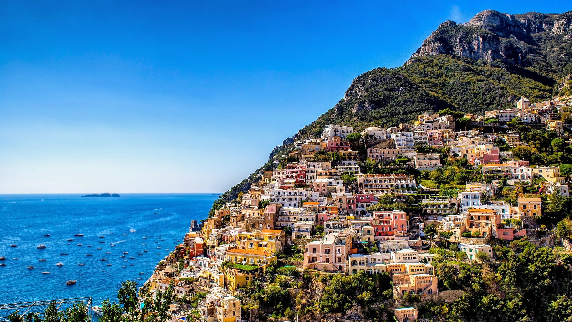 Pastel houses stacked up the cliffside above the turquoise sea at Positano on the Amalfi Coast